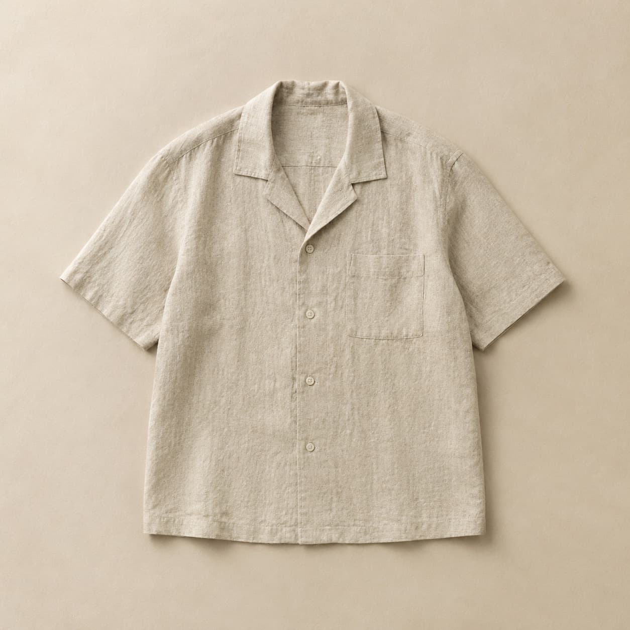 Natural-coloured camp collar linen shirt laid flat showing visible weave texture.