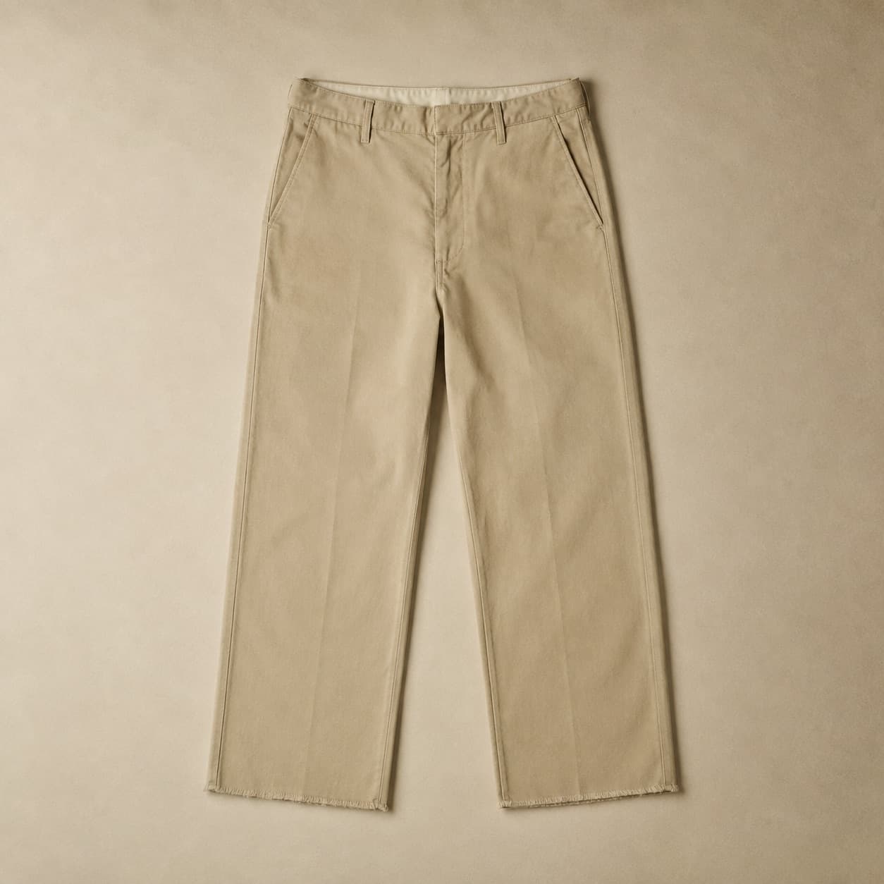 Sand-coloured straight-leg trousers laid flat with the unfinished hem visible.