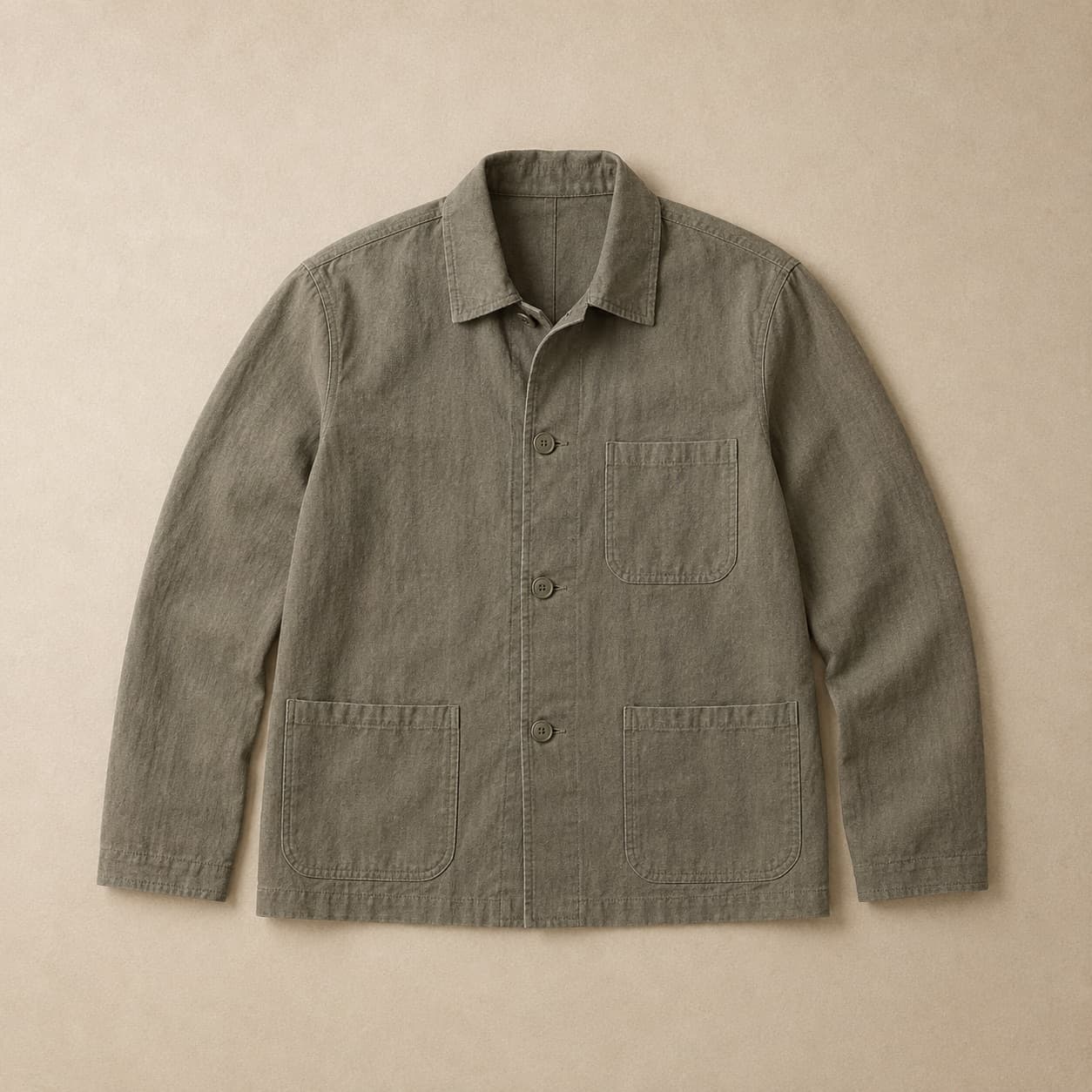 Olive-grey chore jacket with three patch pockets laid flat.