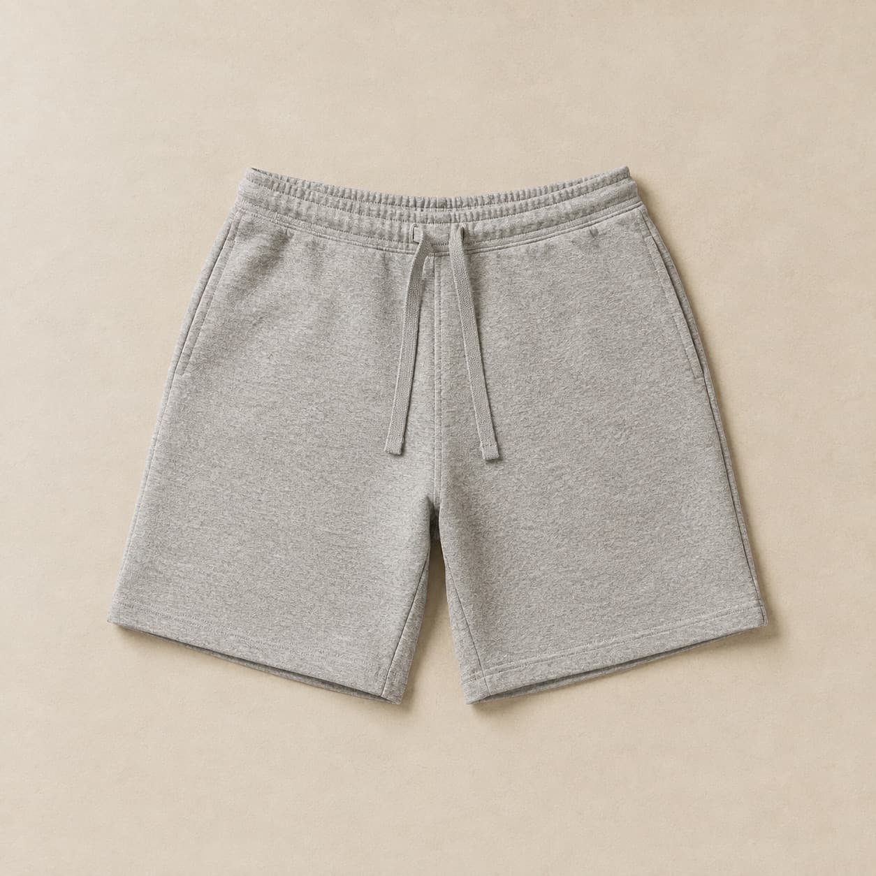 Grey mid-thigh sweat shorts laid flat with a flat drawcord at the waist.