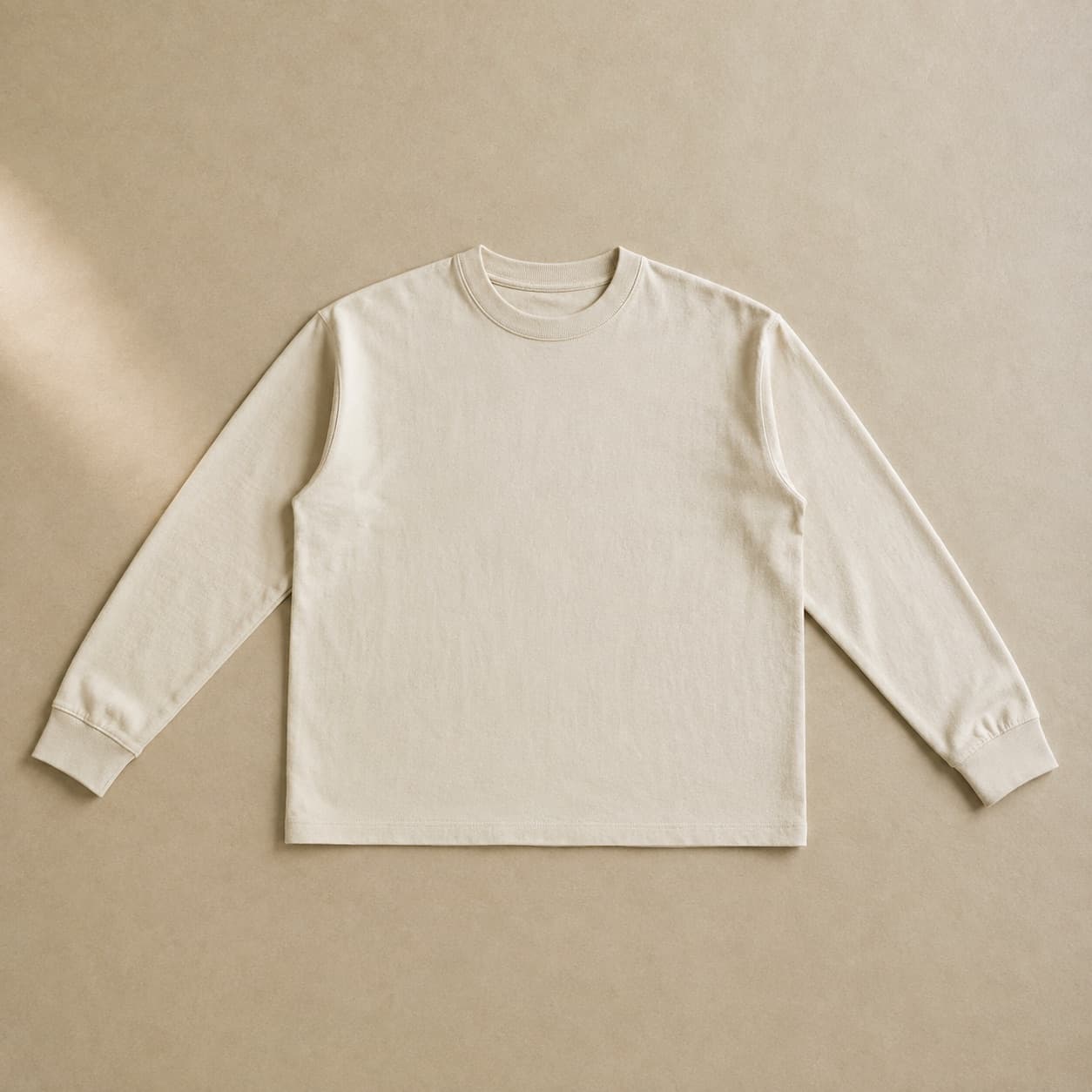 Ecru long-sleeve top laid flat with sleeves straight.