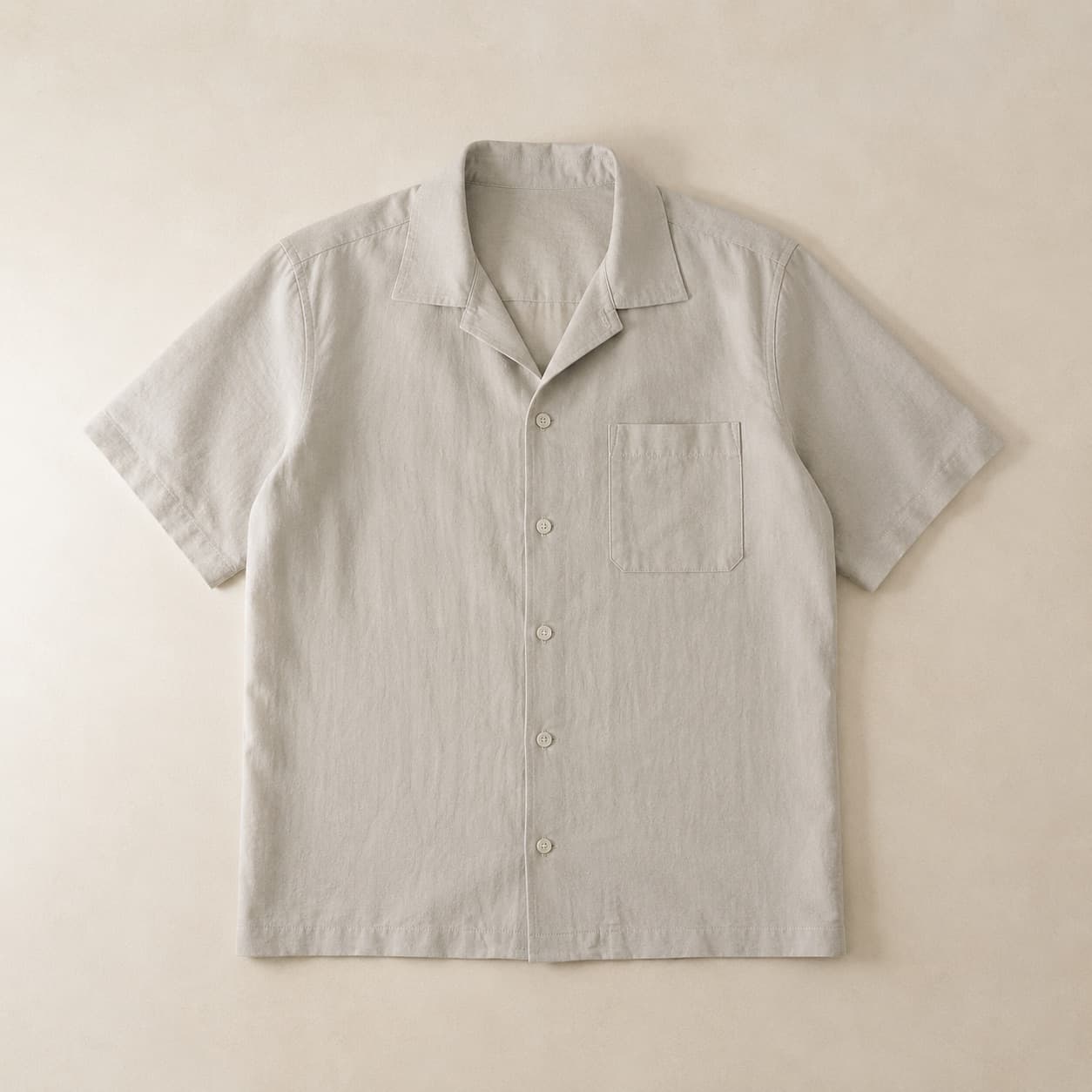 Pale grey button-through shirt laid flat with the collar open.