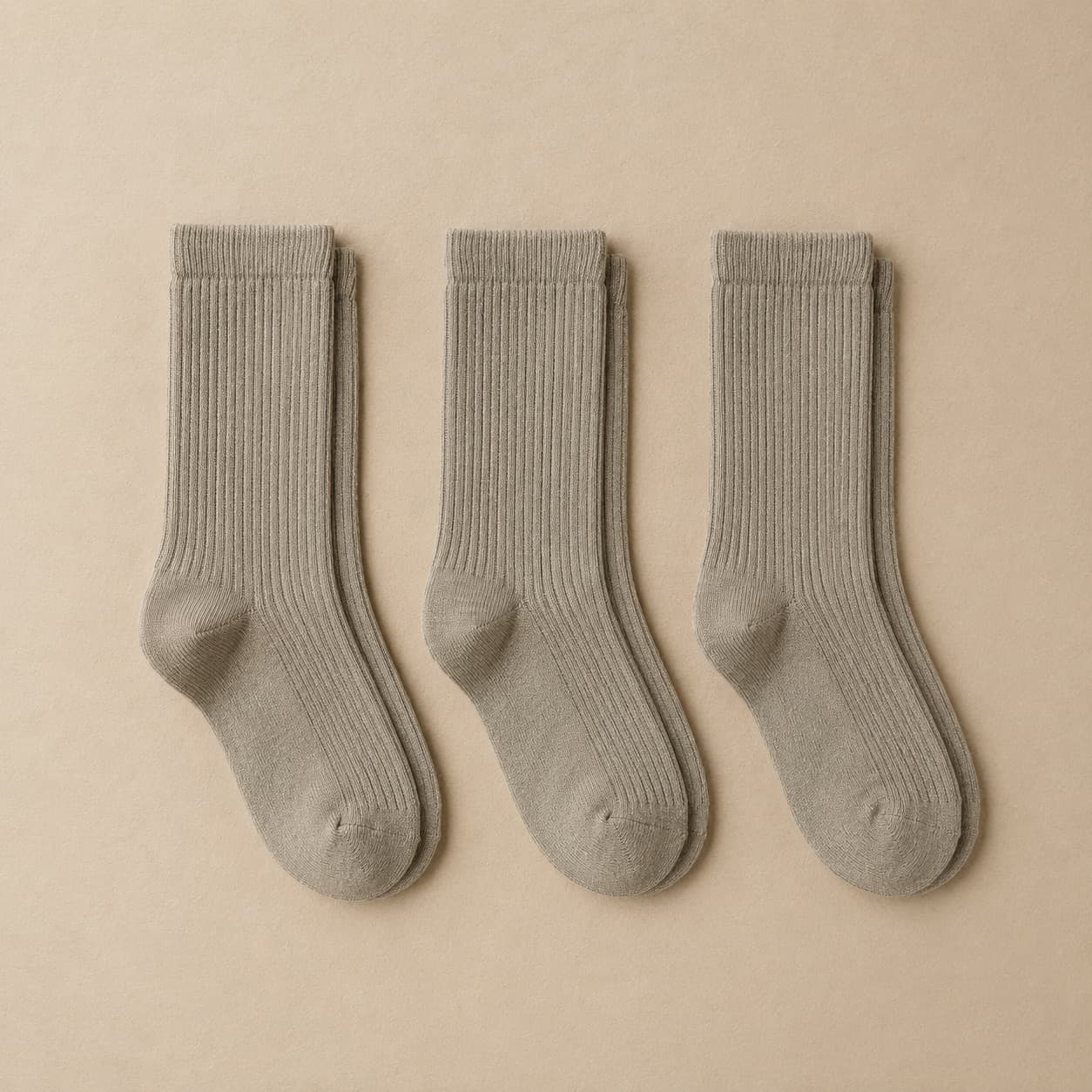 Three pairs of grey ribbed socks laid flat in a row.