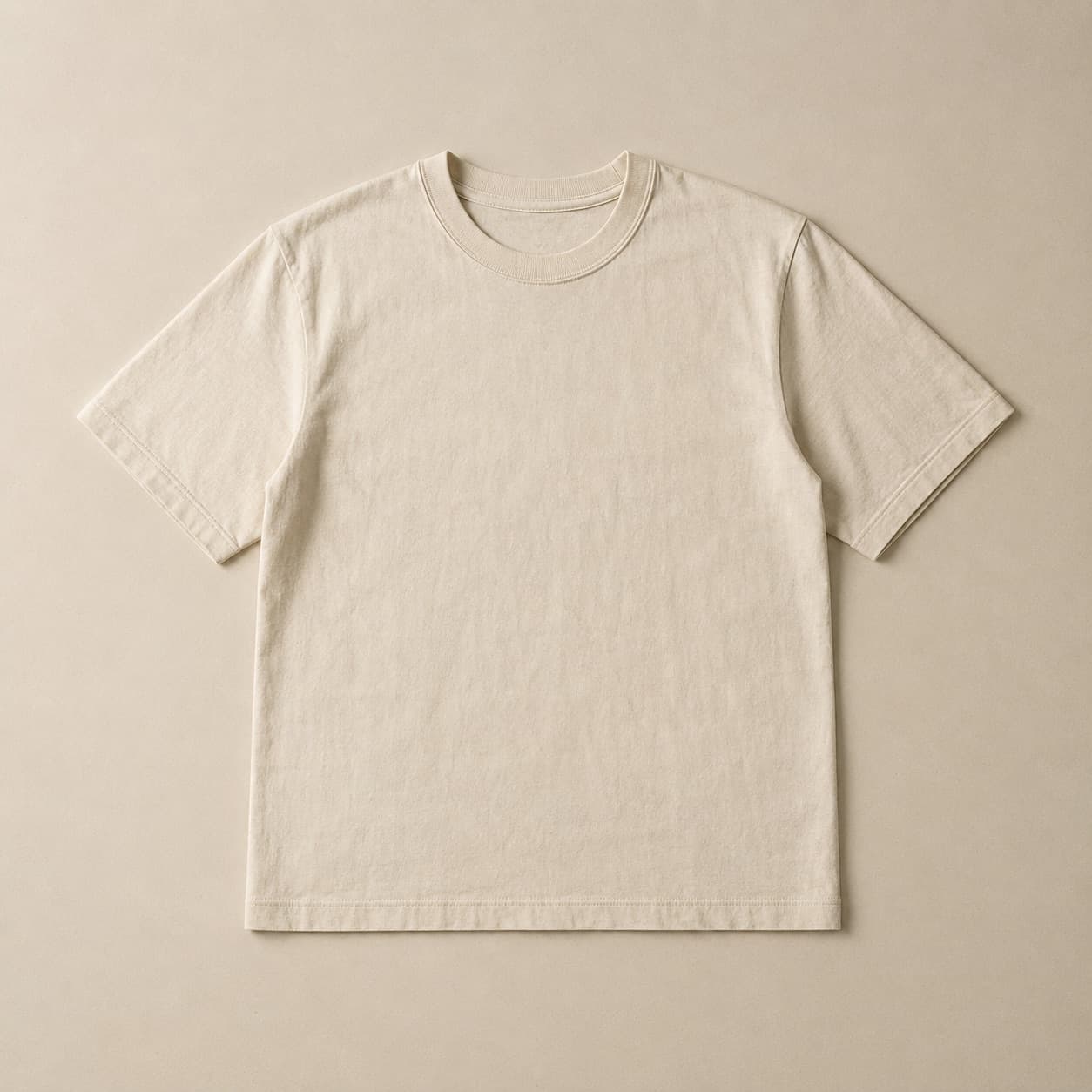 Ecru short-sleeve tee laid flat on a pale linen surface.