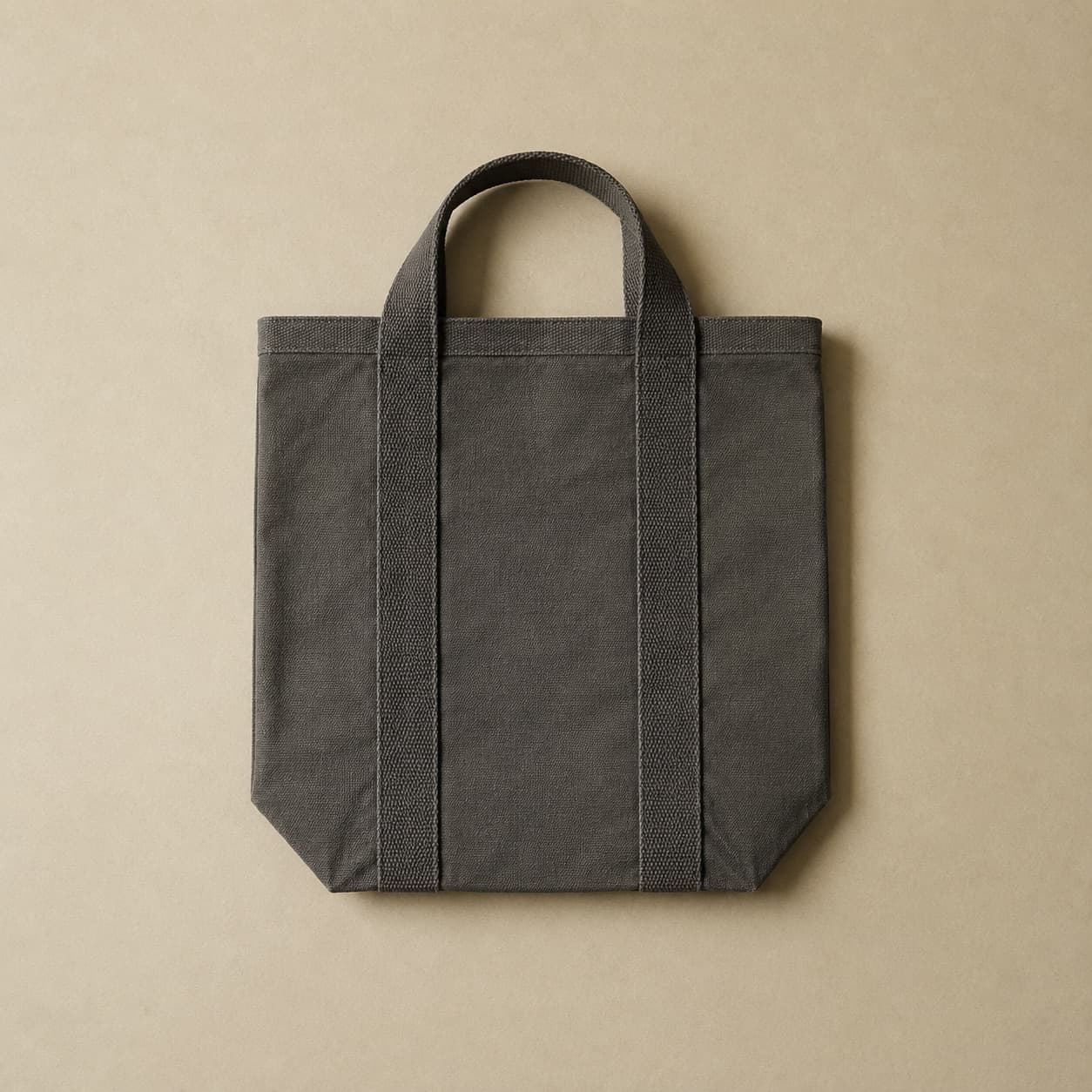 Structured dark grey fabric tote with webbing handles standing upright.