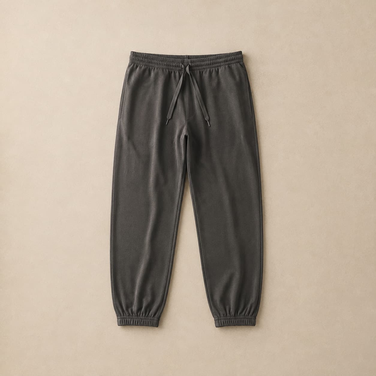 Charcoal track pants laid flat with elasticated ankles.