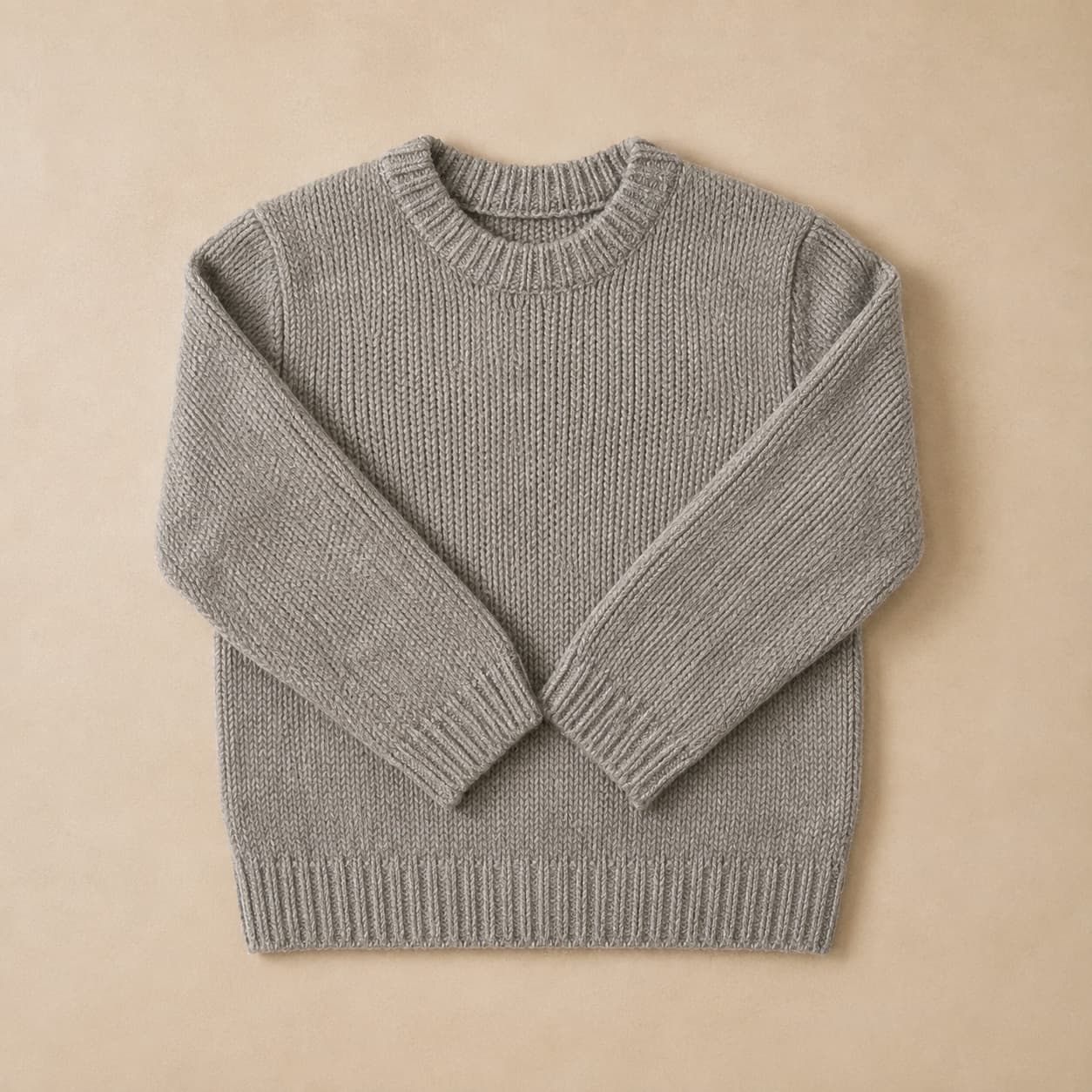 Heather grey crew-neck knitted jumper laid flat with sleeves folded in.