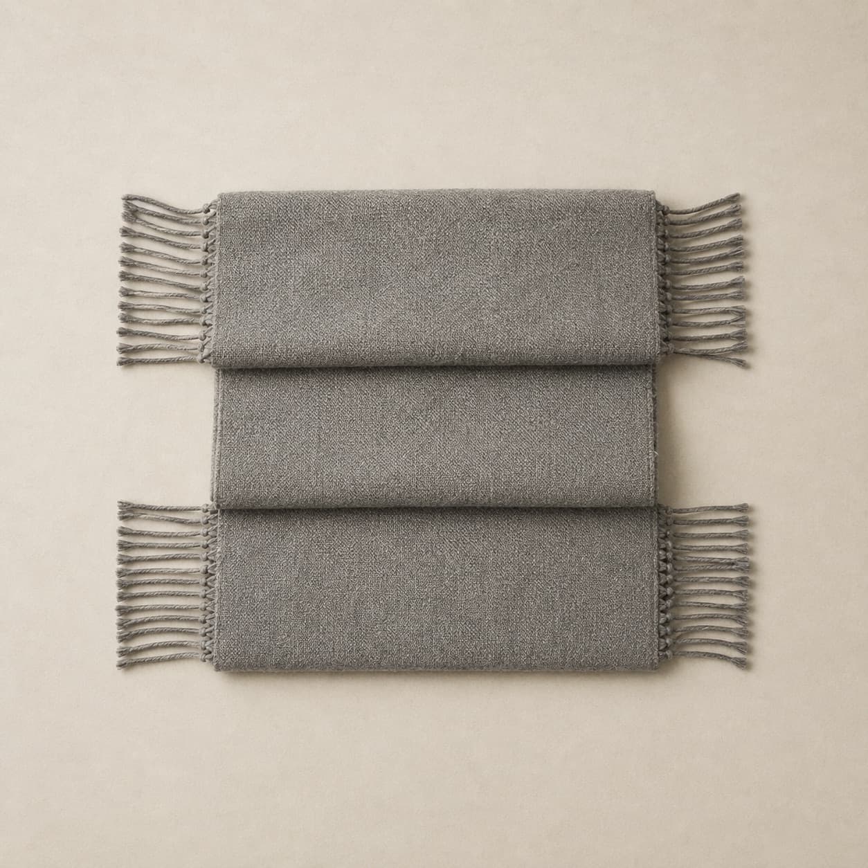 Long grey woven scarf folded in three with knotted fringe visible.