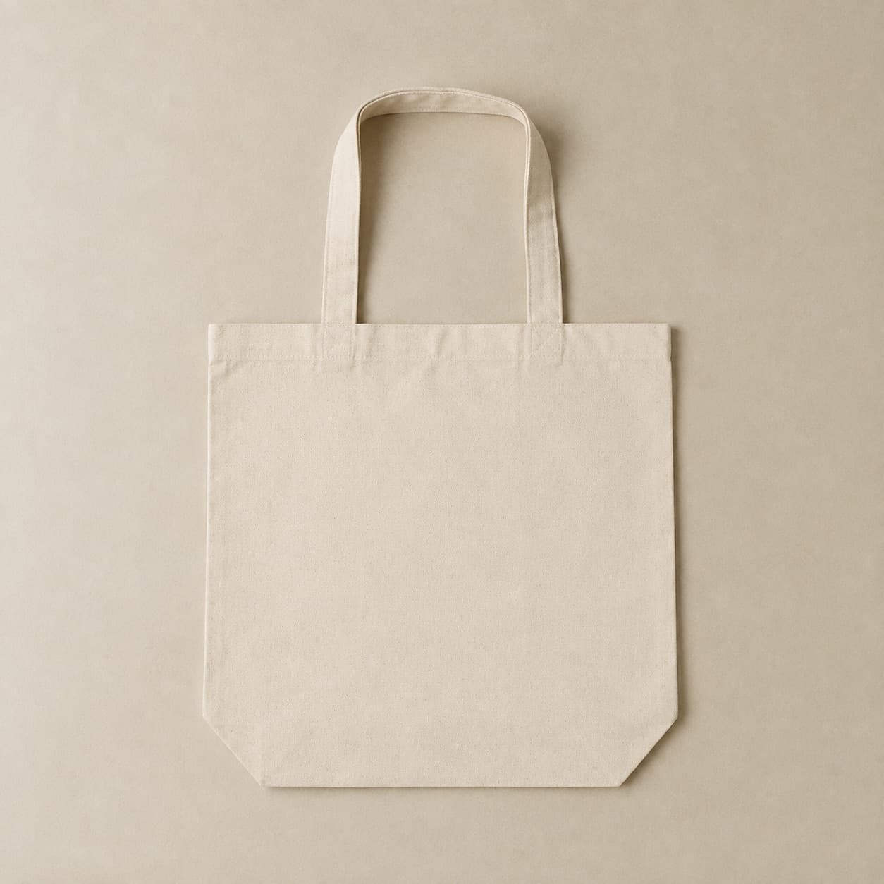 Undyed natural canvas tote bag laid flat with two straight handles.