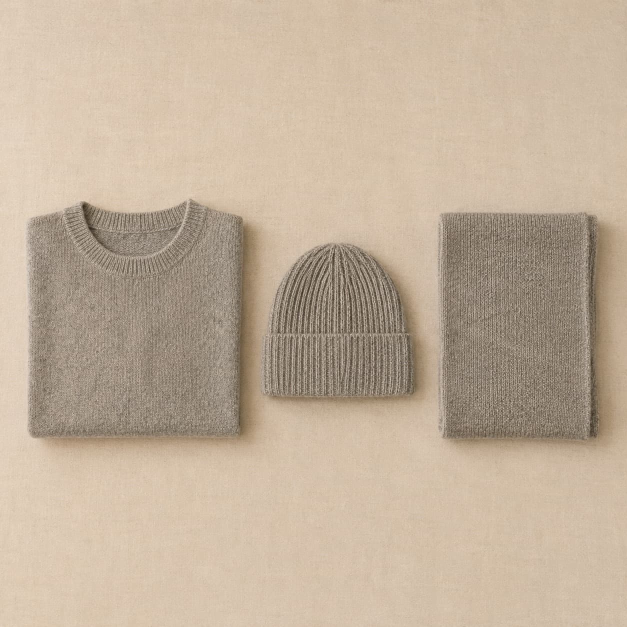 A knitted jumper, a ribbed beanie and a folded scarf laid flat together.